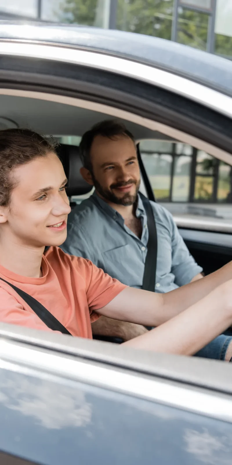 happy-teenage-boy-holding-steering-wheel-while-dri-2024-11-13-16-07-49-utc